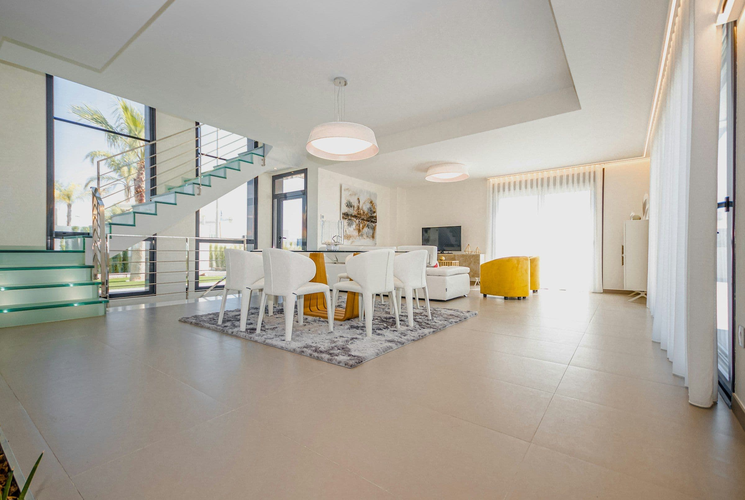 Bright white open-plan villa with a glass floating staircase