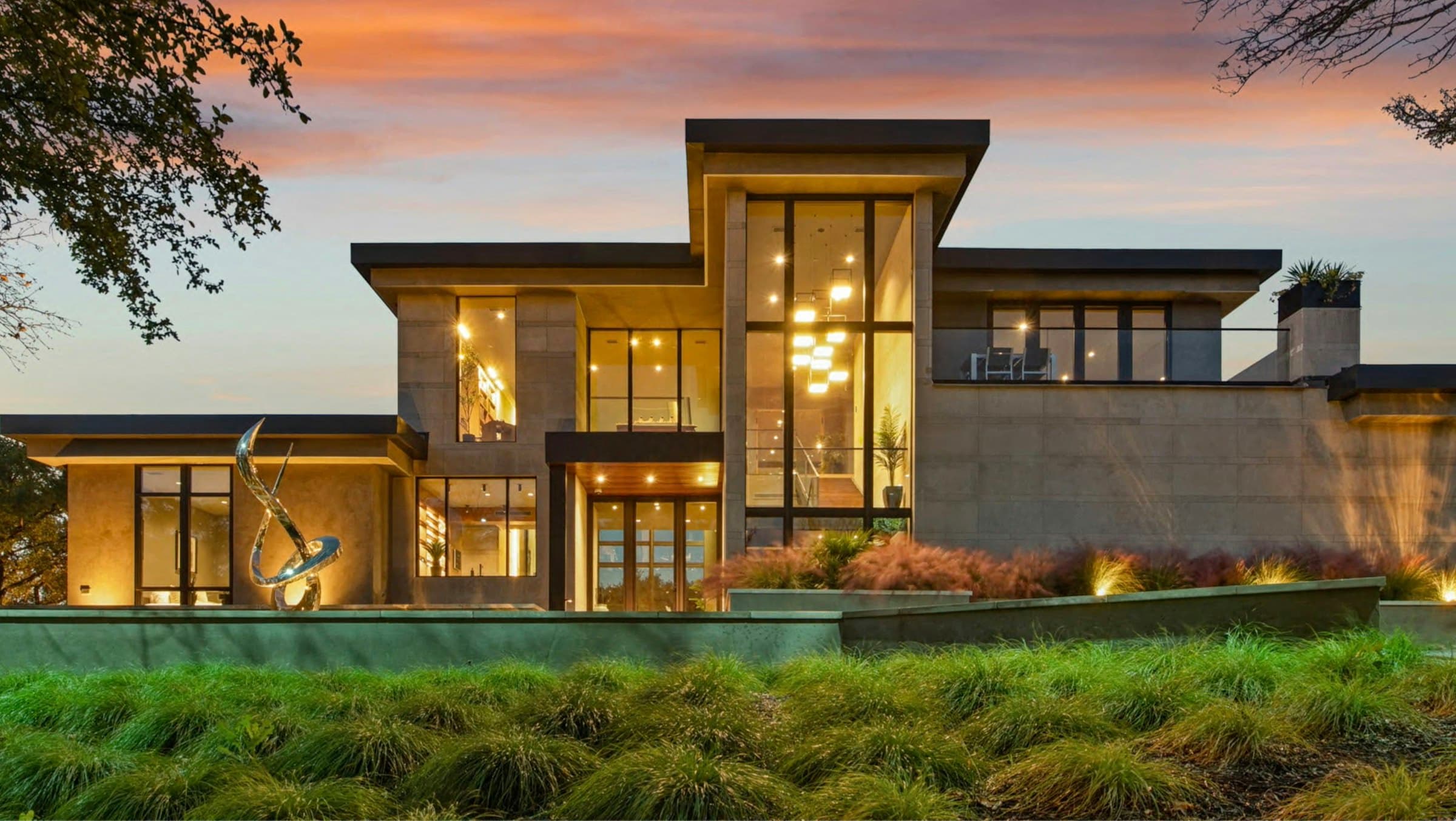Contemporary luxury home glowing with warm interior light at dusk