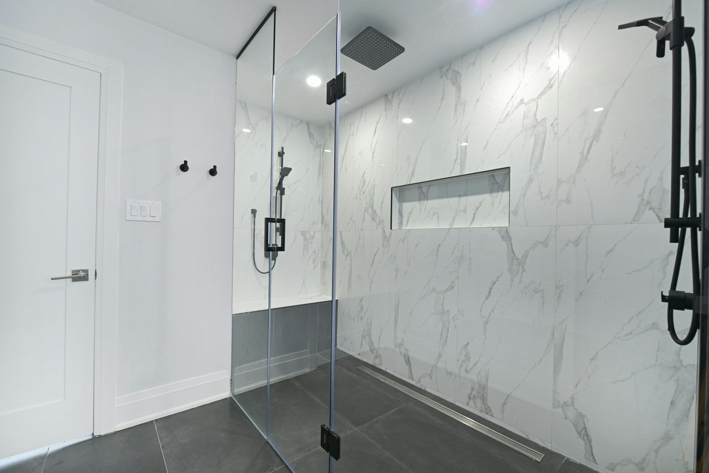 Frameless glass walk-in shower with white marble walls