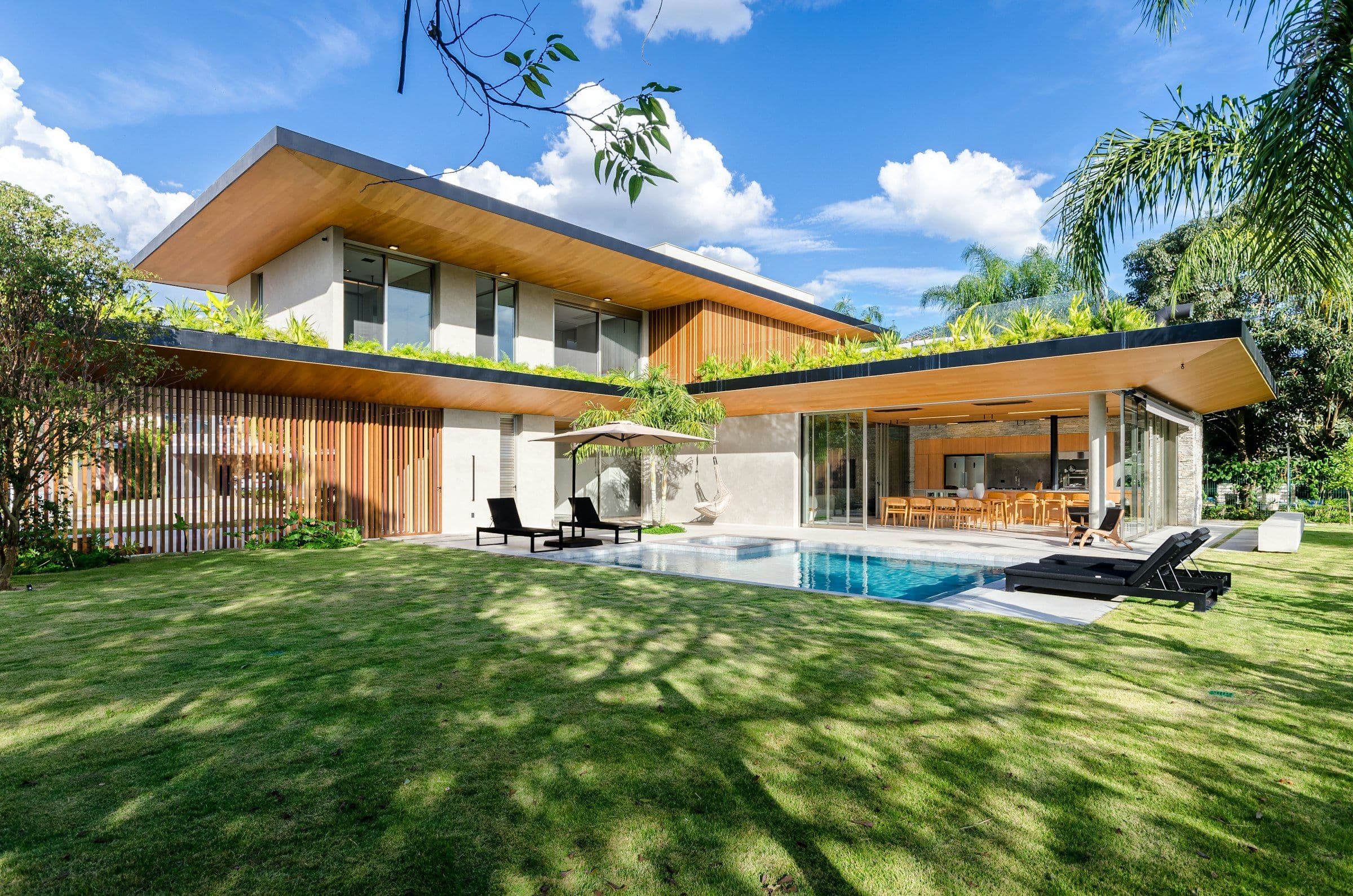 Contemporary estate with a long pool, broad lawn and palms
