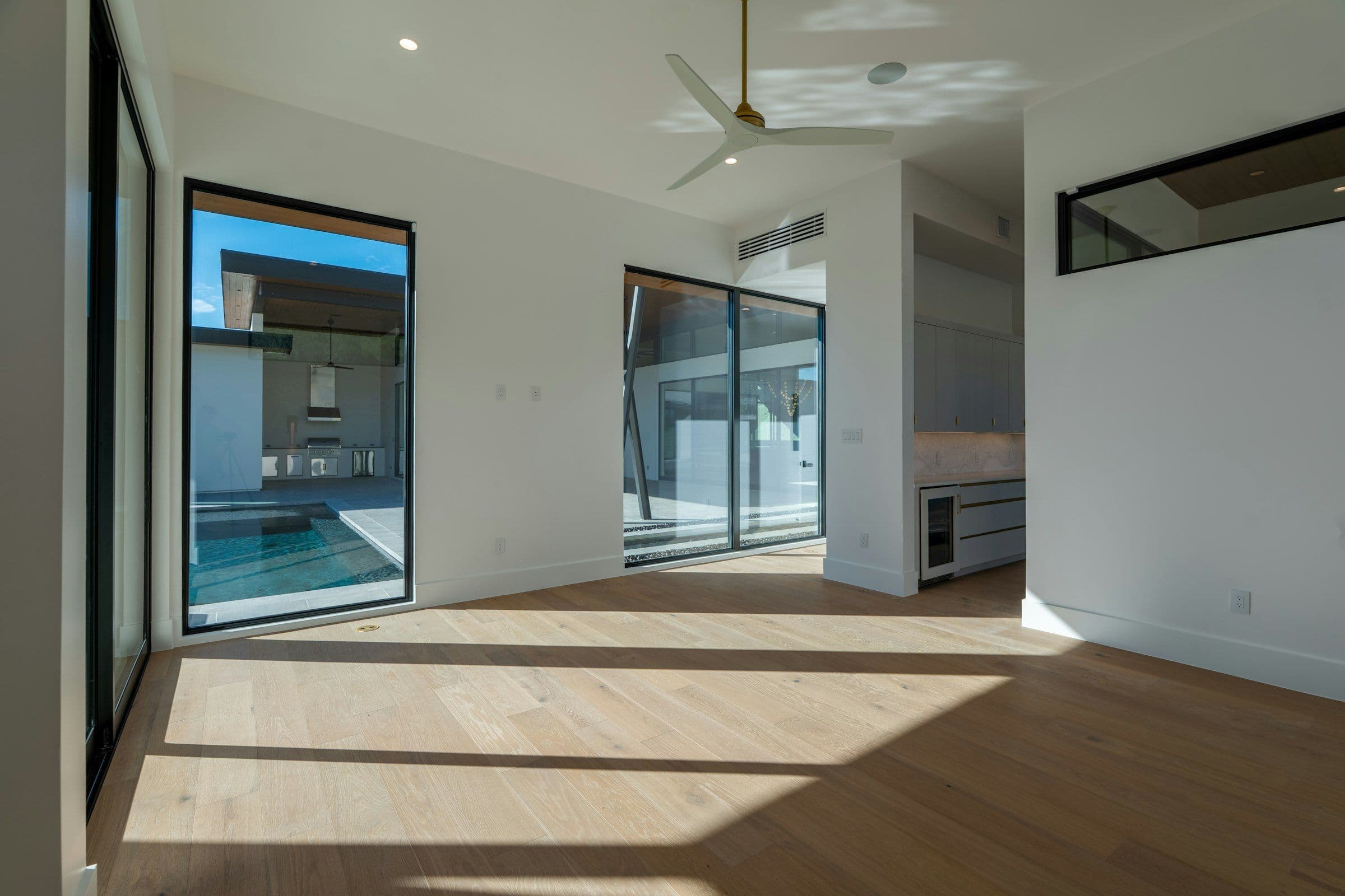 Newly built great room with oak floors and glass doors onto the pool