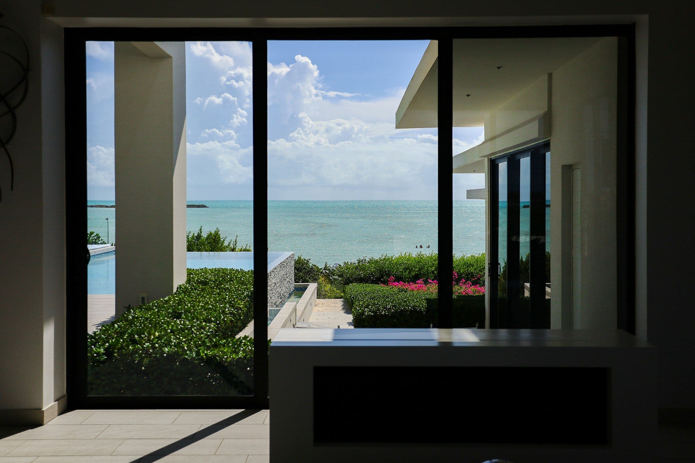 Black-framed glass doors opening onto an infinity pool and the ocean