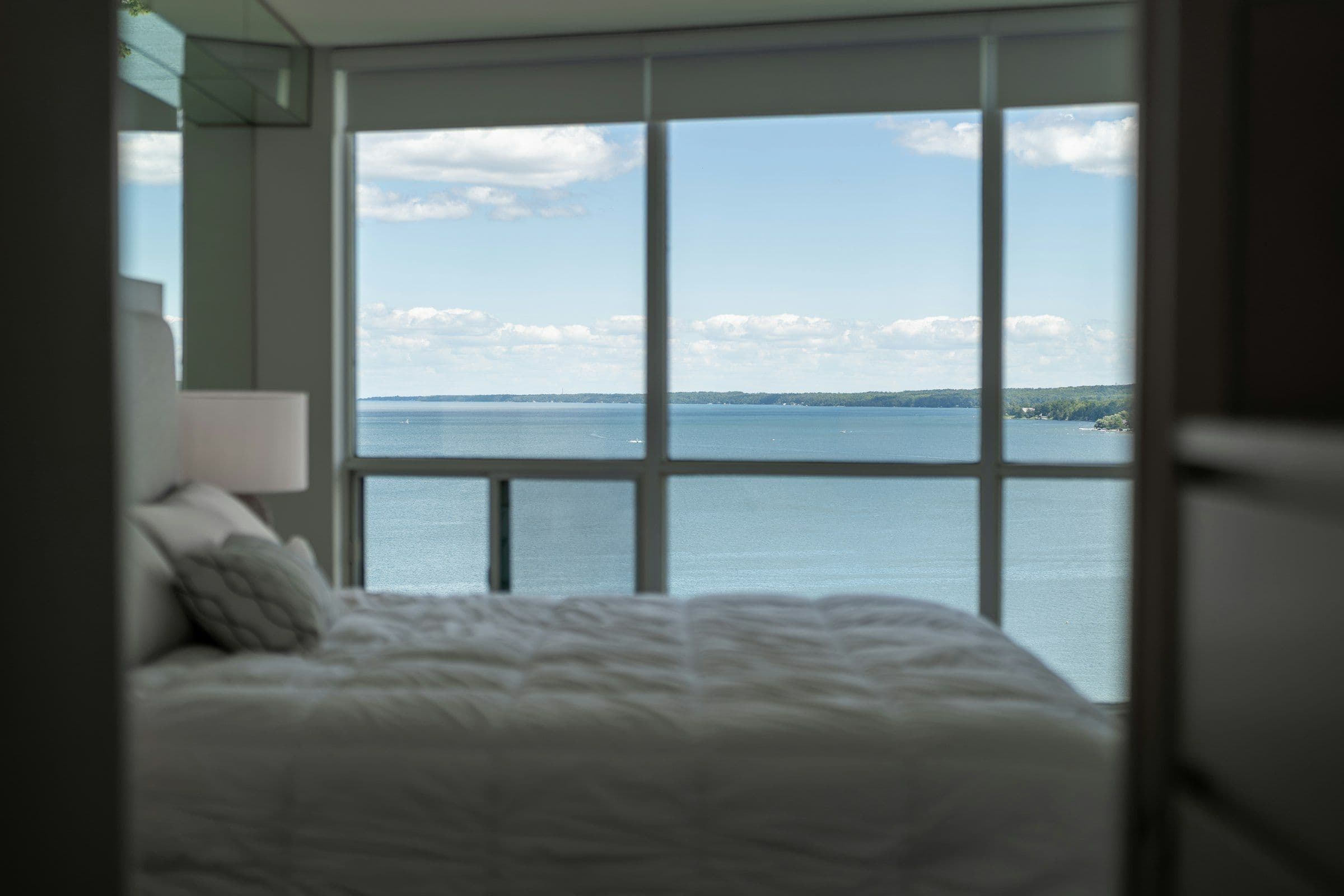 Bedroom with a window wall overlooking open blue water