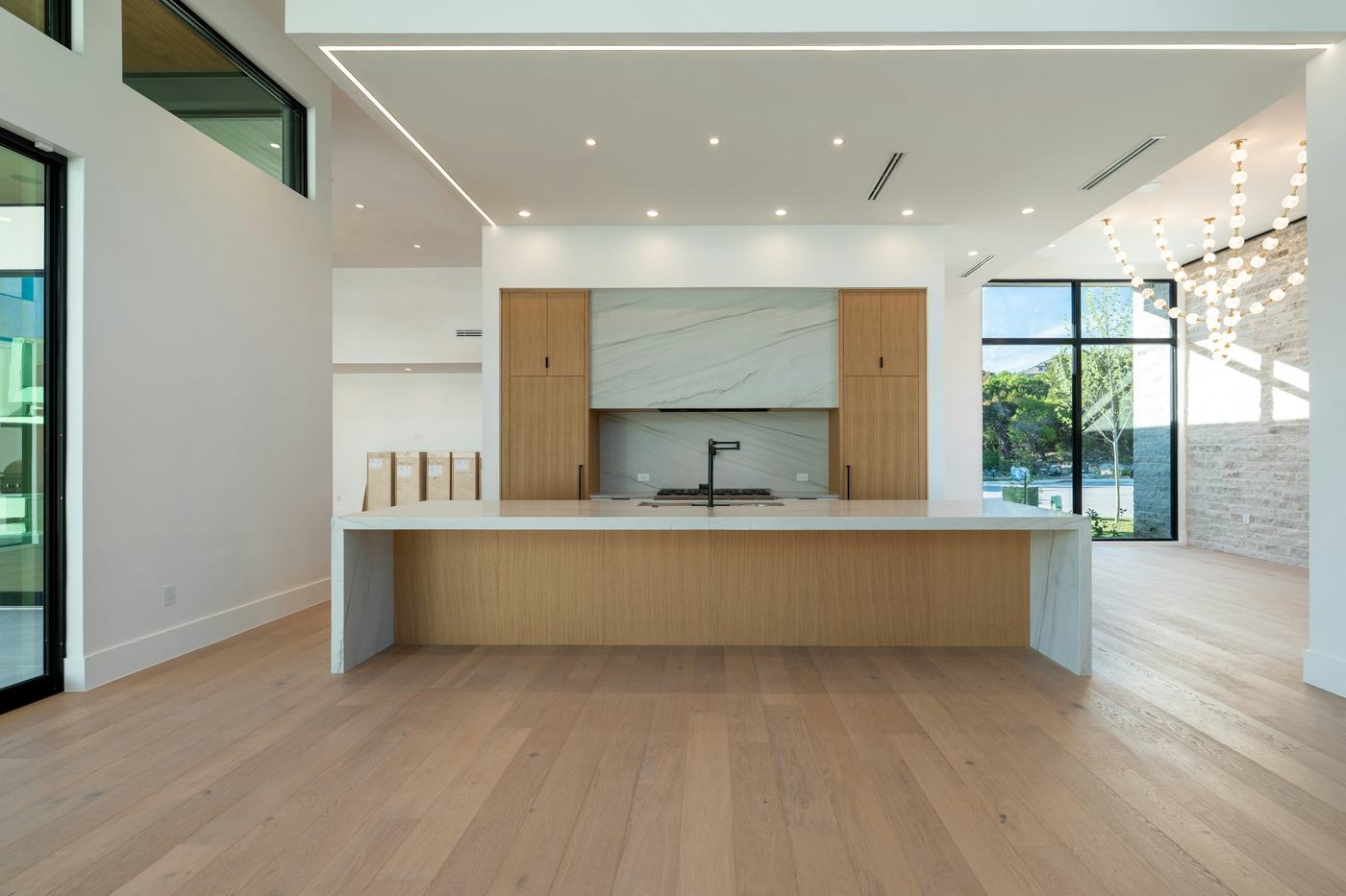 Newly built kitchen with a long white island and oak floors